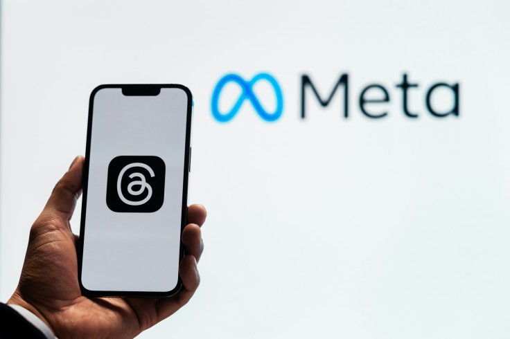 Threads app logo on phone held in front of Meta