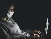 Person with mask using MacBook