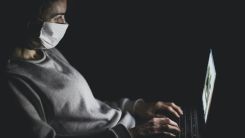 Person with mask using MacBook