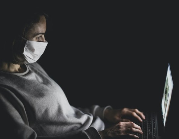 Person with mask using MacBook